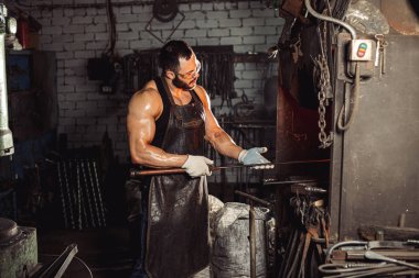 Dikkat et demirci elinde metal tutuyor.