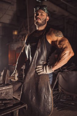 Siyah önlüklü kendinden emin genç metal işçisinin portresi.