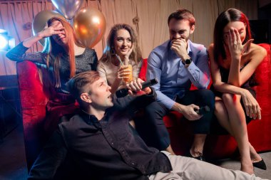 Bir grup genç parti yapıyor, tatil yapıyor, rahatlıyor ve karaoke yapıyor.