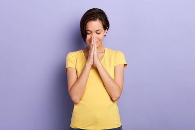 Olumlu, neşeli bir kadın dua ederken ellerini tutar.