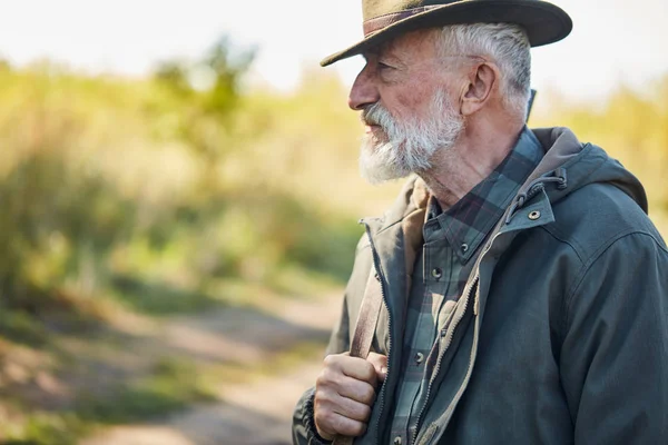 Senior hunter with grey beard in forest