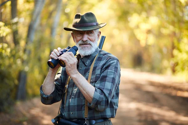 Sorrindo caçador sênior usar binóculos — Fotografia de Stock