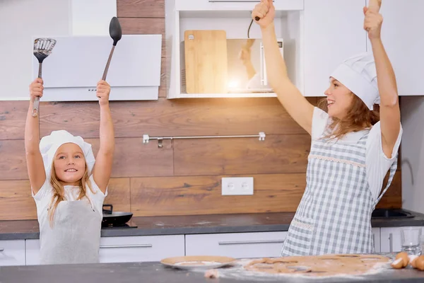 Verspielte fröhliche Frau und Mädchen genießen die Kochzeit in der Küche — Stockfoto