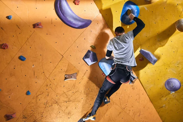 カラフルなホールドと岩と物理的に挑戦男クライミング壁 — ストック写真