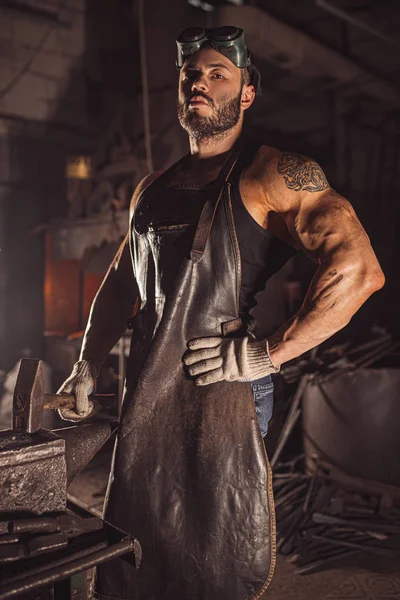 Retrato de un joven metalúrgico confiado y fuerte en delantal negro — Foto de Stock