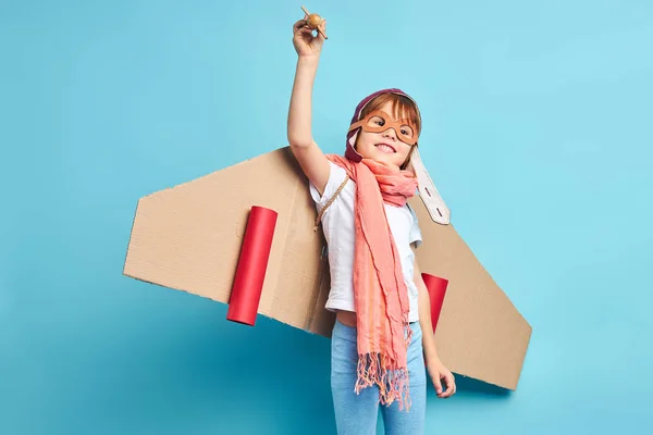 Pilot boy with cardboard plane isolated over blue background