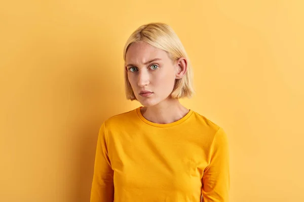 Серьезная скептическая женщина в моде желтый свитер позирует перед камерой — стоковое фото