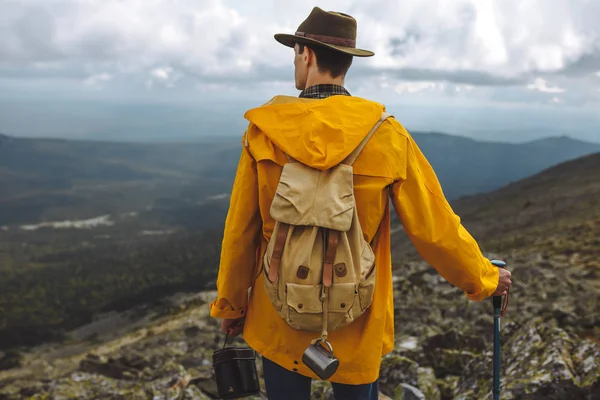 Mladý muž ve žlutém plášti tráví čas v horách — Stock fotografie