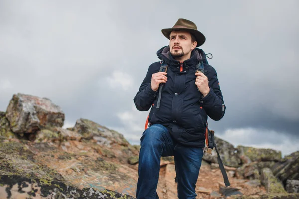 Turista em chapéu verde, casaco azul andando na montanha — Fotografia de Stock