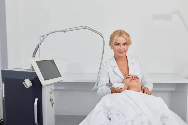 Therapist smoothing womans wrinkles , preventing the threat of skin cancer — Stock Photo, Image