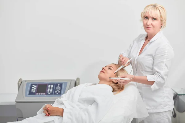 Blondynka utalentowany kosmetolog wykonujący zabieg mikroprądowy w salonie piękności — Zdjęcie stockowe