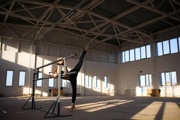 Гибкая маленькая гимнастка, занимающаяся акробатическими упражнениями в спортзале — стоковое фото