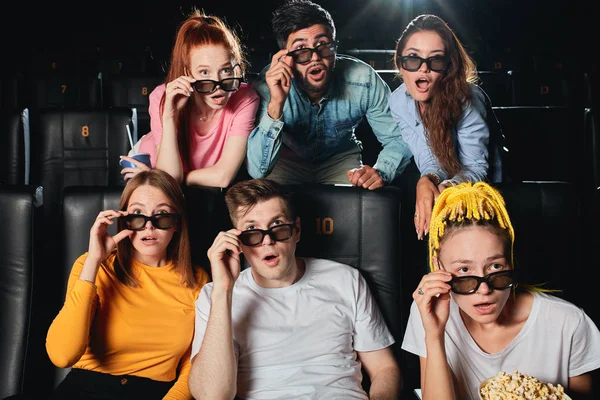 Vrienden die hun bril aanraken en naar de film staren — Stockfoto