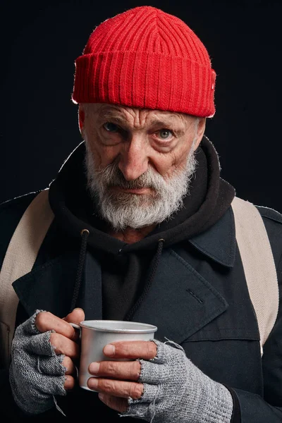Senior sem-teto homem tentando se aquecer com caneca de bebida quente — Fotografia de Stock