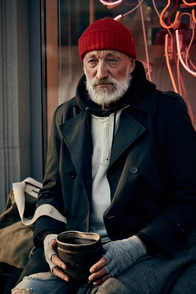 Homeless senior man sitting in street and begging — Stock Photo, Image