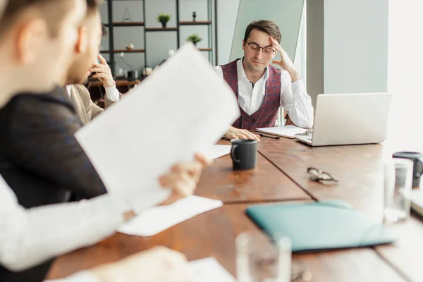 Busy men in tux sit on table in office — 스톡 사진