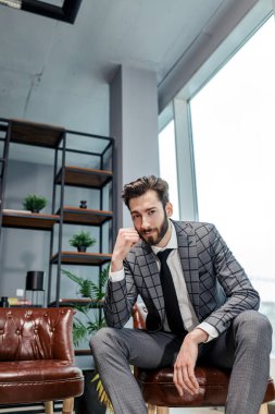 Smokinli yetişkin adam kendi ofisinde oturuyor.