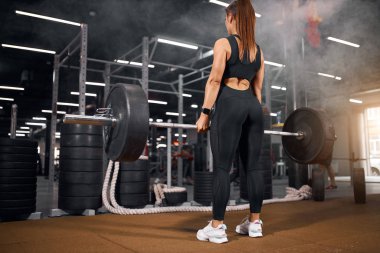 Spor salonundaki kadın halterle egzersiz yapıyor.