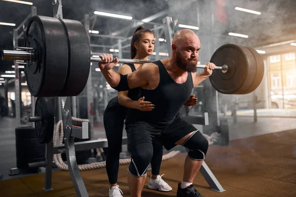 Brutal hombre con beutiful entrenador en el gimnasio —  Fotos de Stock