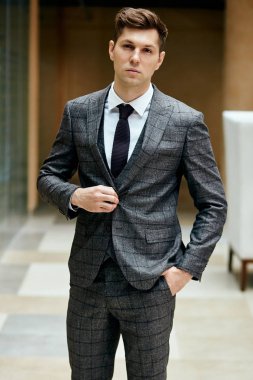 Dışarıda duran takım elbiseli ve kravatlı yakışıklı genç adam.