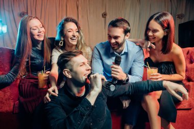 Genç beyaz insanlar karaoke kulübünde dans edip şarkı söylüyorlar.