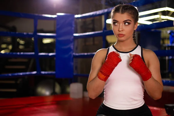 young MMA girl in sports uniform ready to fight in boxing ring