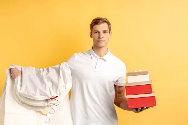 Agradável jovem entregador com caixas e roupas — Fotografia de Stock