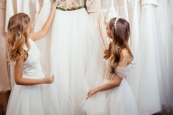 Duas belas mulheres jovens escolhendo um vestido de noiva no salão — Fotografia de Stock