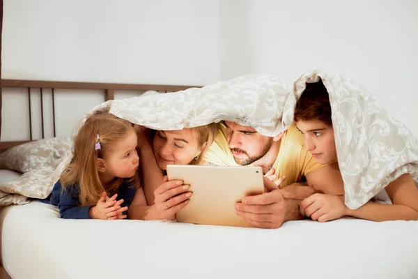 Crianças e pais bonitos juntos na cama — Fotografia de Stock