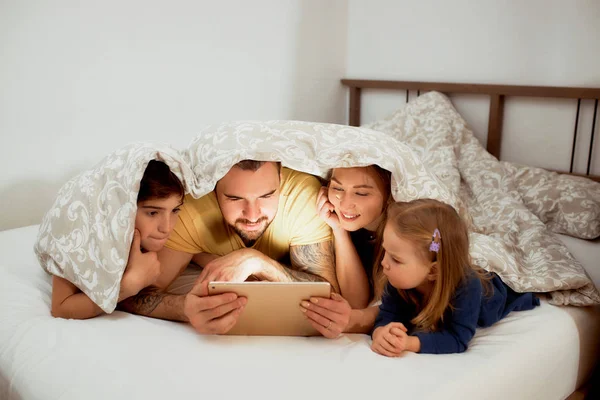 Crianças e pais bonitos juntos na cama — Fotografia de Stock