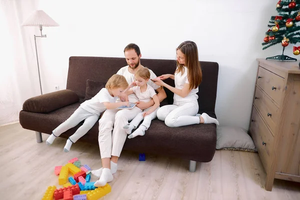 Біла сім'я використовує планшет вдома, сидячи на дивані — стокове фото