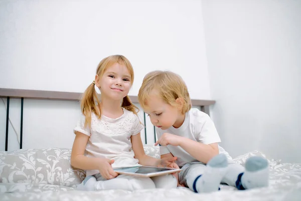 Niños atractivos utilizan gadget moderno, sosteniendo la tableta en las manos — Foto de Stock