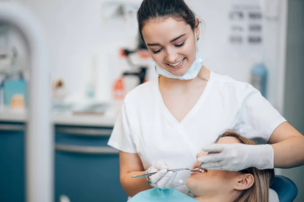 Voorzichtige professionele tandarts vrouw behandeling van tanden — Stockfoto