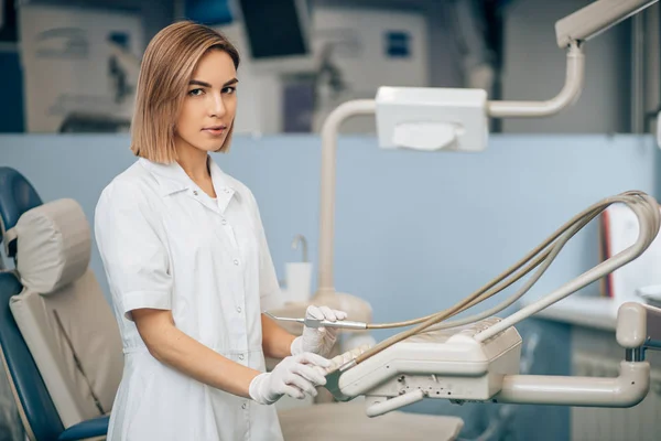 Allvarlig tandläkare kvinna som använder medicinsk utrustning på jobbet — Stockfoto