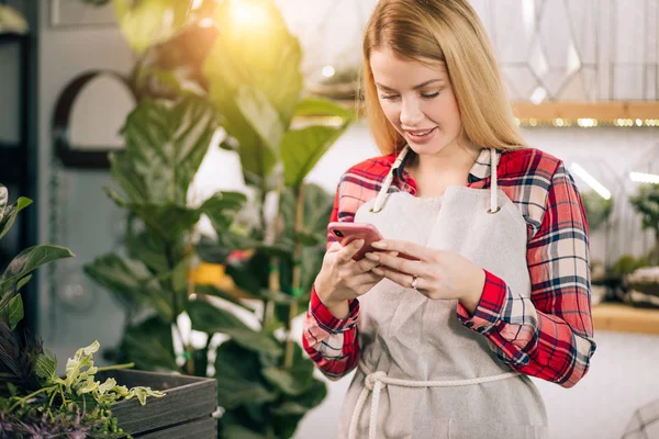 Smiling lady florist with mobile phone at work — Stock Photo, Image