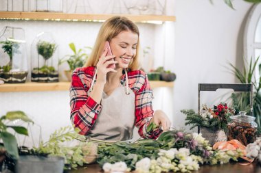 Akıllı telefonlu güzel bir çiçekçi kadın.
