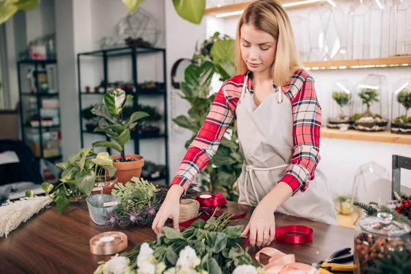 Vacker glad ung florist hona står i växthus full av blommor — Stockfoto