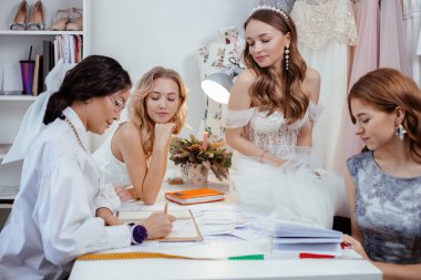 good-looking designer tailor of wedding dresses and young women