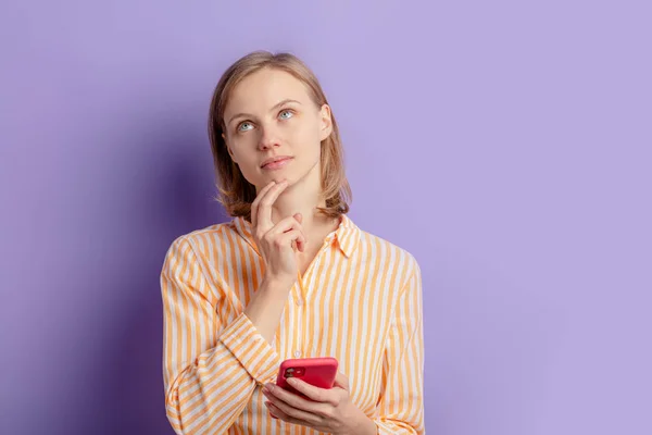 Cute young woman think holding smartphone — Stock Photo, Image