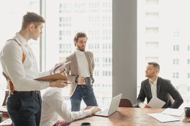 Takım elbiseli kendine güvenen genç adamlar toplantı odasında birlikte çalışıyorlar.