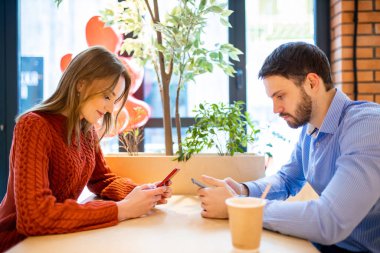 Kafede tablet kullanan genç bir adam ve bir kadın.