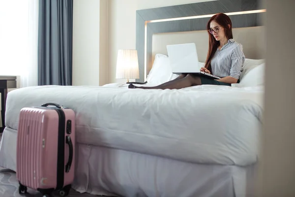 Mujer elegante acostada vestida en la cama con portátil en la habitación del hotel . — Foto de Stock