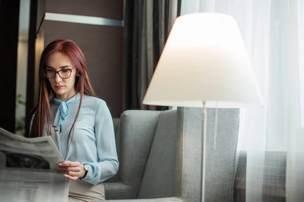 Gelukkig jonge zakenvrouw lezen van de krant in de lobby van het hotel — Stockfoto
