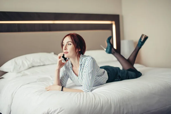 Элегантная стильная деловая женщина в туфлях на каблуках, лежащих на кровати в отеле — стоковое фото