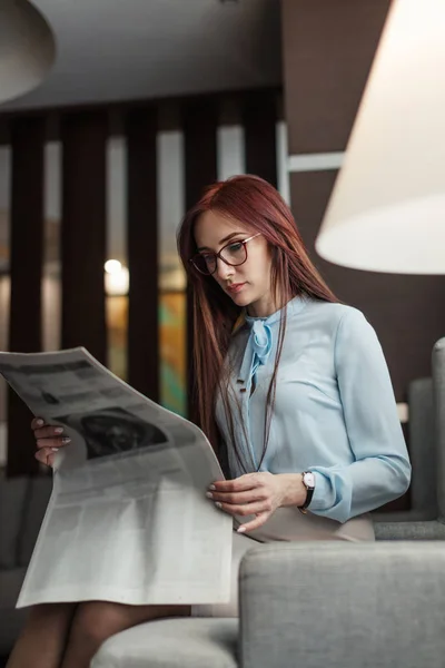 Щаслива молода бізнес-леді читає газету в готельному лобі — стокове фото