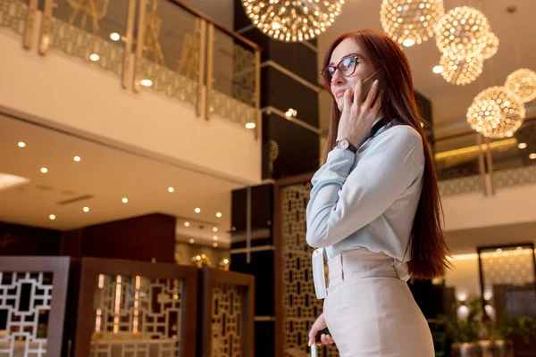 Fotoğraf gülümseyen genç iş kadın otelde akıllı telefon sohbet — Stok fotoğraf