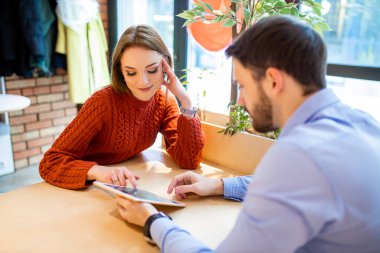 young caucasian couple sit in cafe using tablet