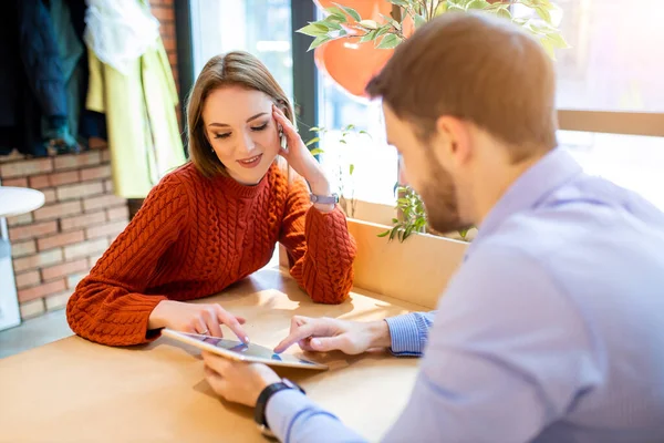 Beautiful man and woman use tablet in modern cafe — Stockfoto