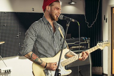 Gitarist aynı anda gitar çalar ve bir şarkı söyler.