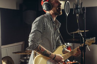 Profesyonel gitarist mikrofonda şarkı söylüyor.